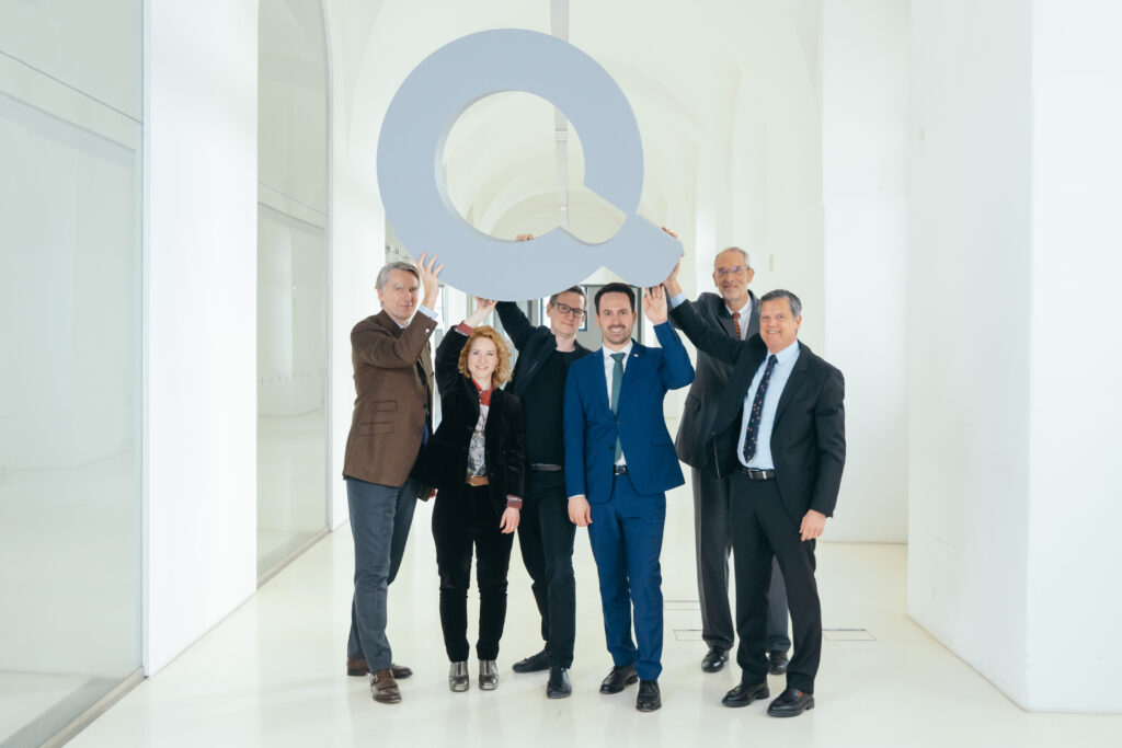 Sebastian Schütze, Eva-Maria Holzleitner, Christopher Lindinger, Christoph Wiederkehr, Jens Schneider, Heinz Faßmann halten ein Modell des Q-Logos in die Höhe..